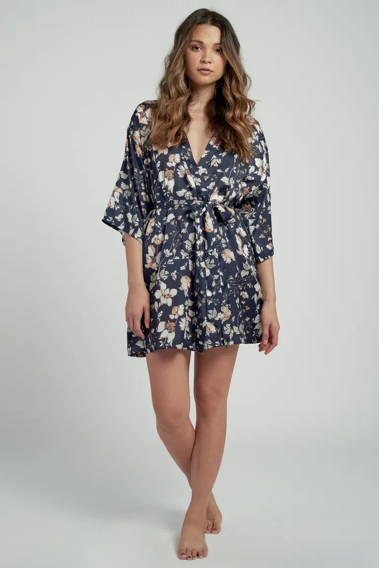 Young brunette model wearing a short, printed satin robe with detachable sash.